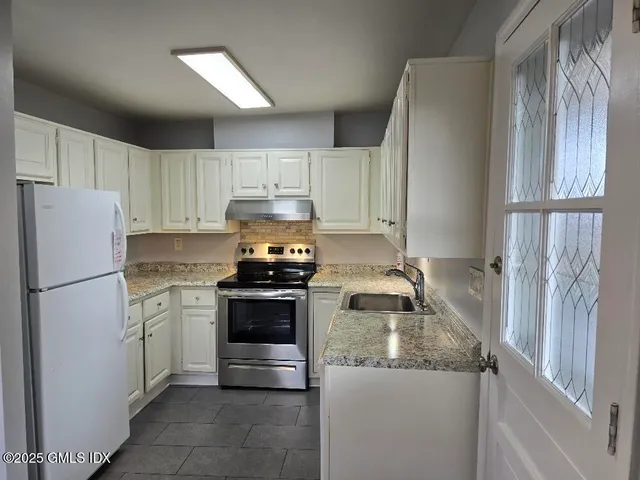 a kitchen with granite countertop a refrigerator stove and sink