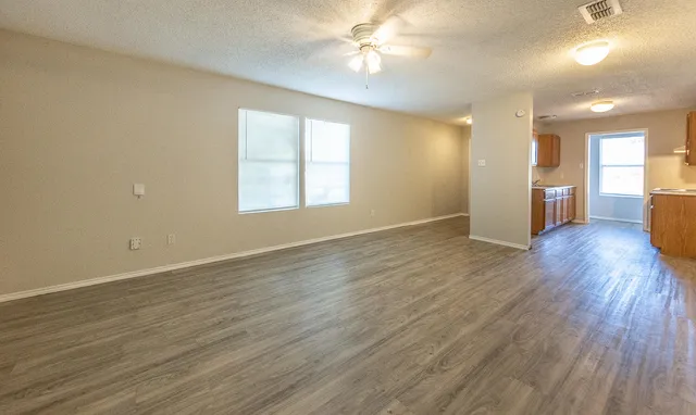 an empty room with wooden floor and windows