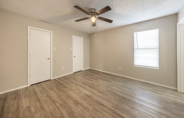 an empty room with wooden floor and windows