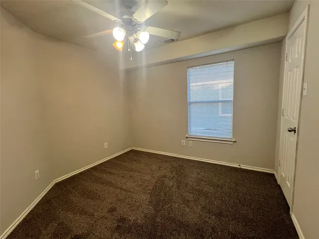an empty room with a chandelier fan and windows