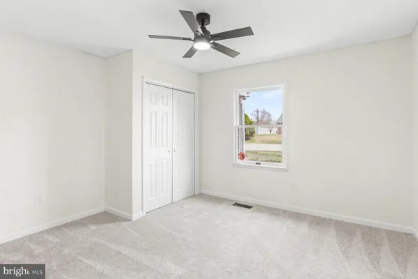 an empty room with a window and a ceiling fan