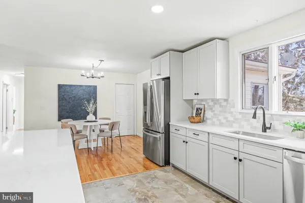 a kitchen with stainless steel appliances granite countertop a refrigerator a sink a stove a dining table and chairs