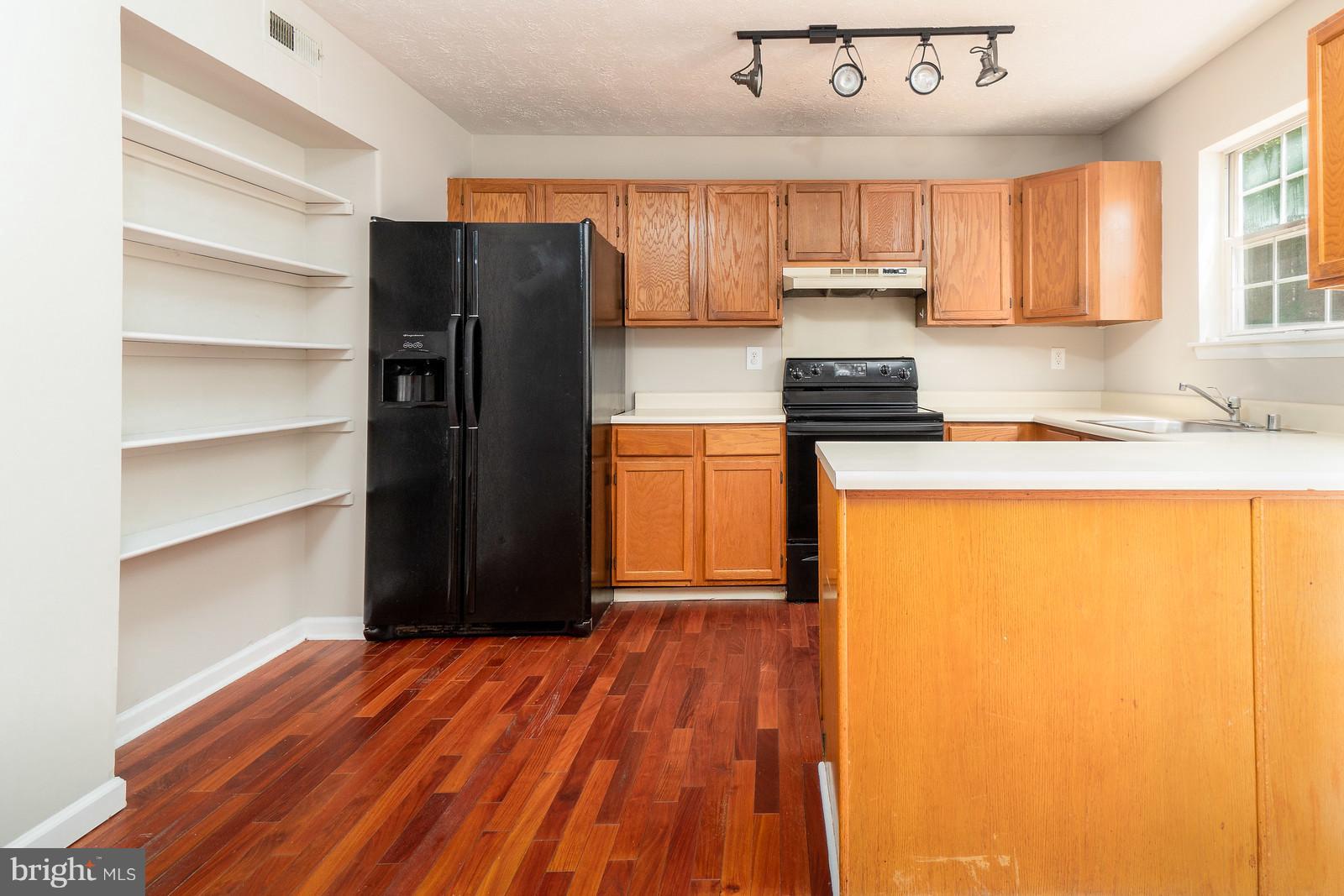 4083 Rustico Road Baltimore, MD 21220 - Photo 10 of 25 a kitchen with granite countertop wooden cabinets and a refrigerator