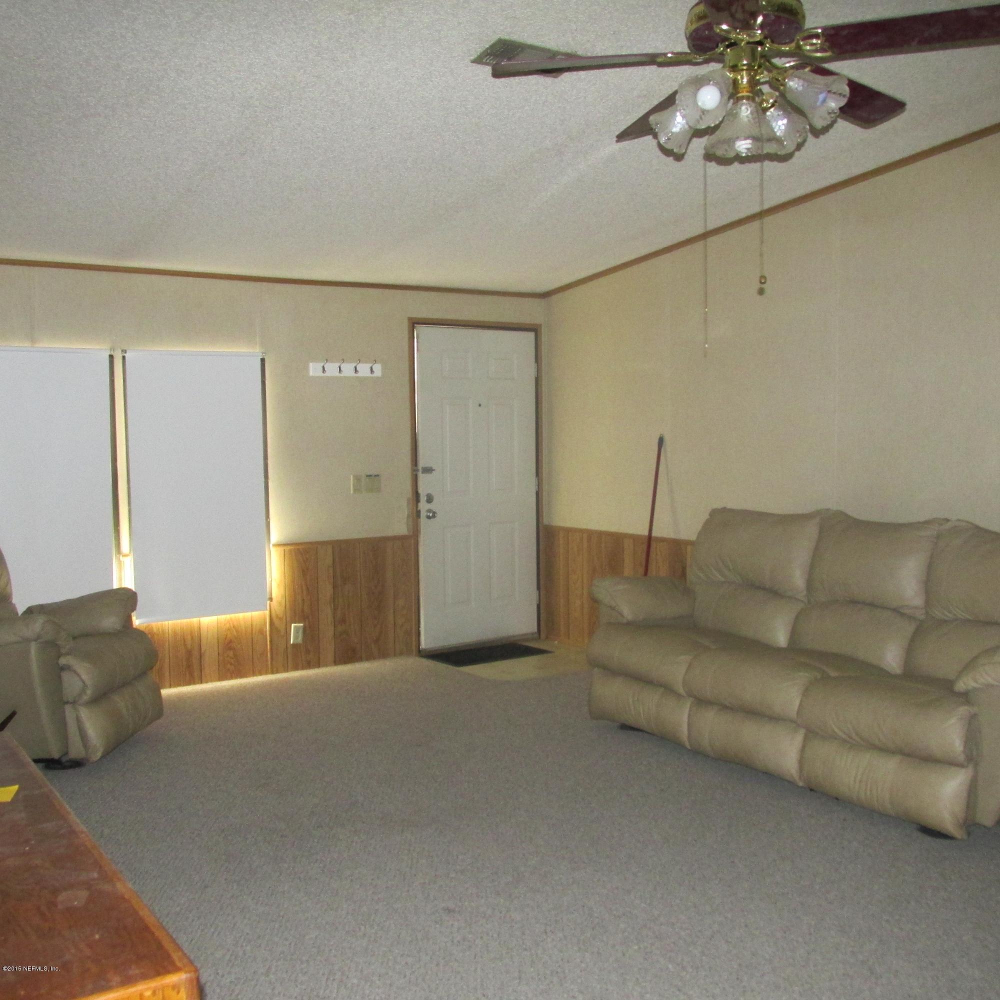 6841 Deer Springs Road Keystone Heights, FL 32656 - Photo 5 of 27 a living room with furniture and a chandelier
