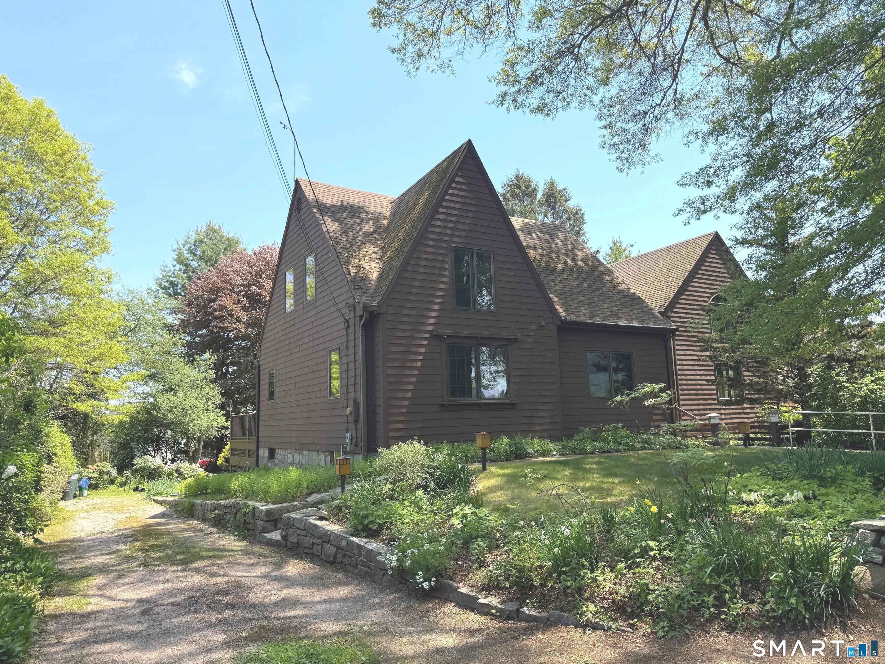 a brick house with a yard plants and large tree