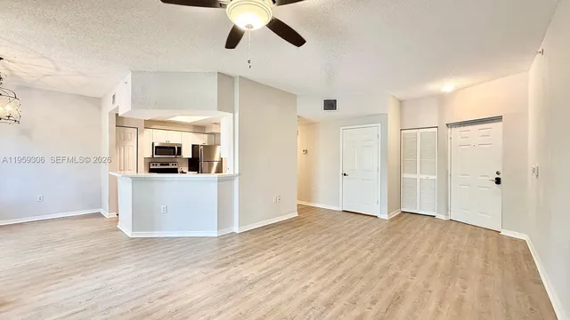 a view of a kitchen with wooden floor a sink a refrigerator and window