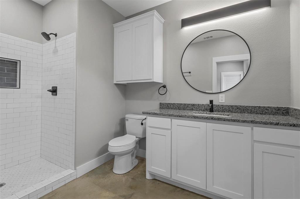 1401 South 5th Avenue, Unit 1401 Denison, TX 75021 - Photo 10 of 16 a bathroom with a granite countertop toilet a sink and a mirror