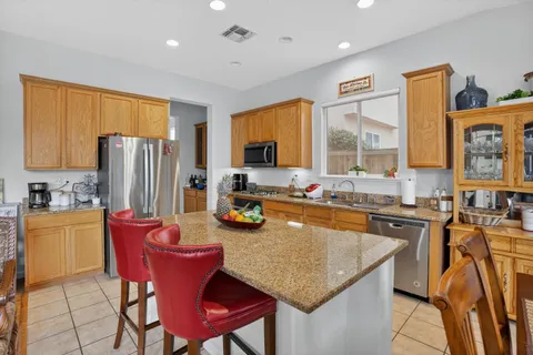 a kitchen with stainless steel appliances granite countertop a kitchen island a stove a refrigerator a table and chairs