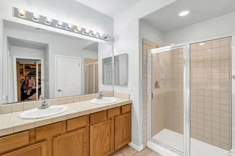 a bathroom with a double vanity sink mirror and shower