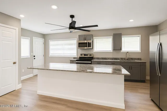 a kitchen with stainless steel appliances granite countertop a sink a stove and a refrigerator