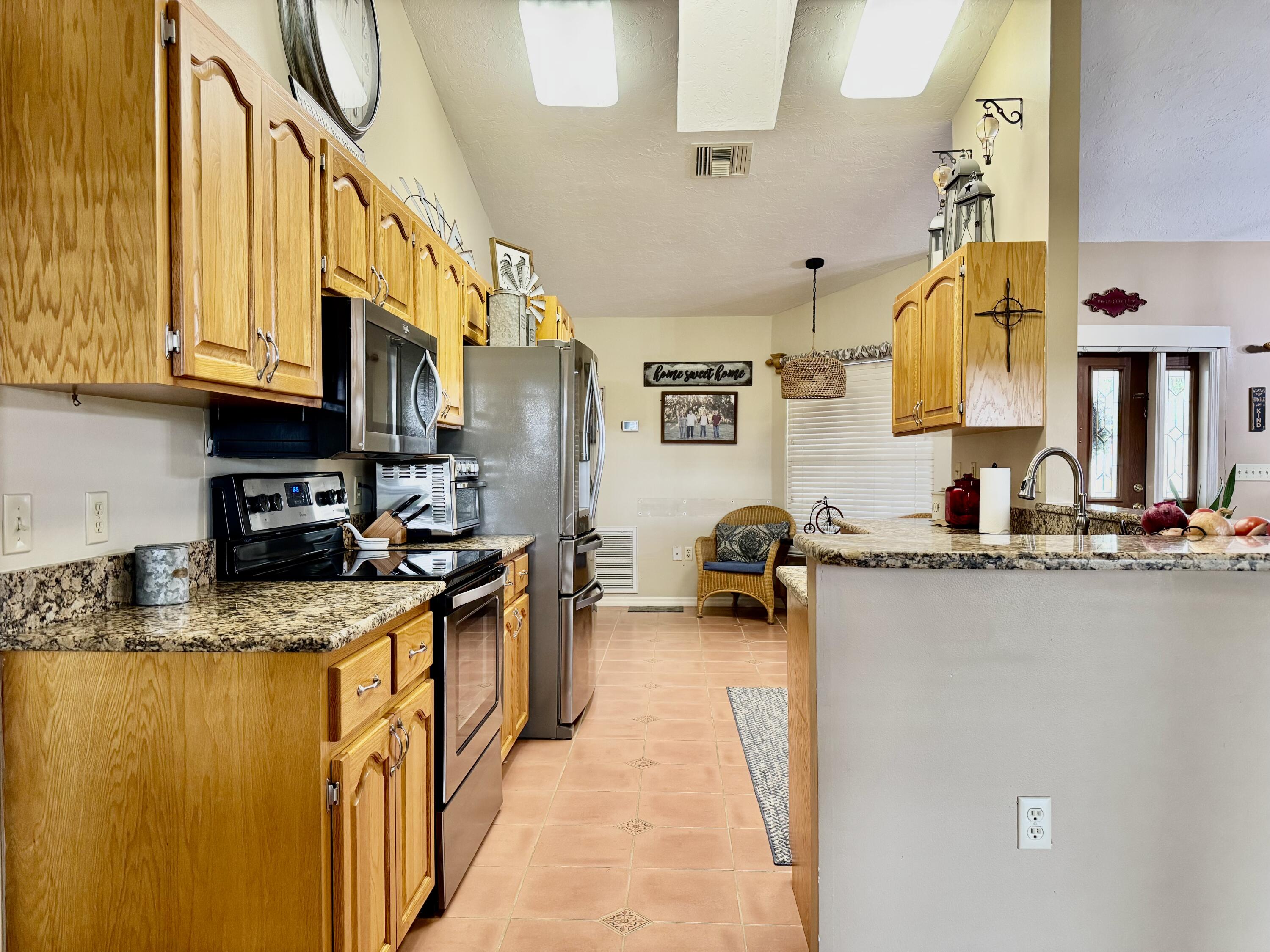 603 Southwest 15th Street Okeechobee, FL 34974 - Photo 5 of 40 a kitchen with stainless steel appliances granite countertop a sink a stove and a wooden cabinets