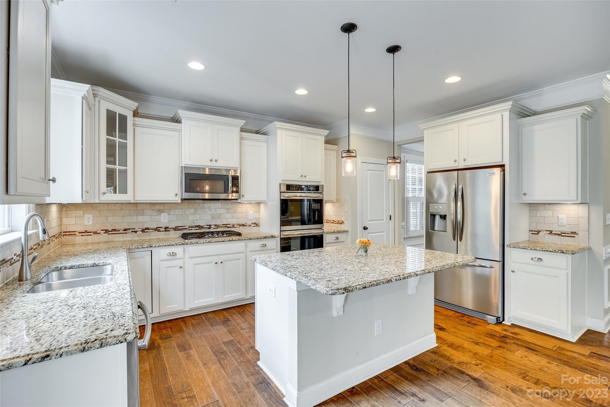 868 Coralbell Way Tega Cay, SC 29708 - Photo 14 of 45 a large kitchen with stainless steel appliances granite countertop a refrigerator a stove a sink and white cabinets with wooden floor