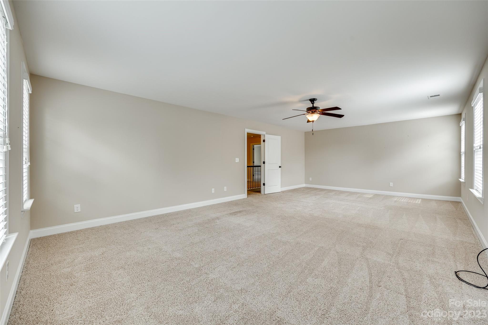 868 Coralbell Way Tega Cay, SC 29708 - Photo 29 of 45 an empty room with a chandelier fan and windows