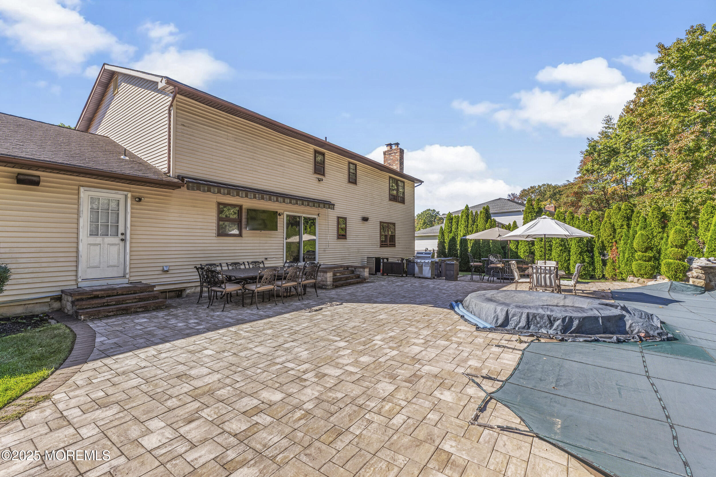 16 Timber Lane Manalapan, NJ 07726 - Photo 43 of 54 a patio with a table and chairs under an umbrella
