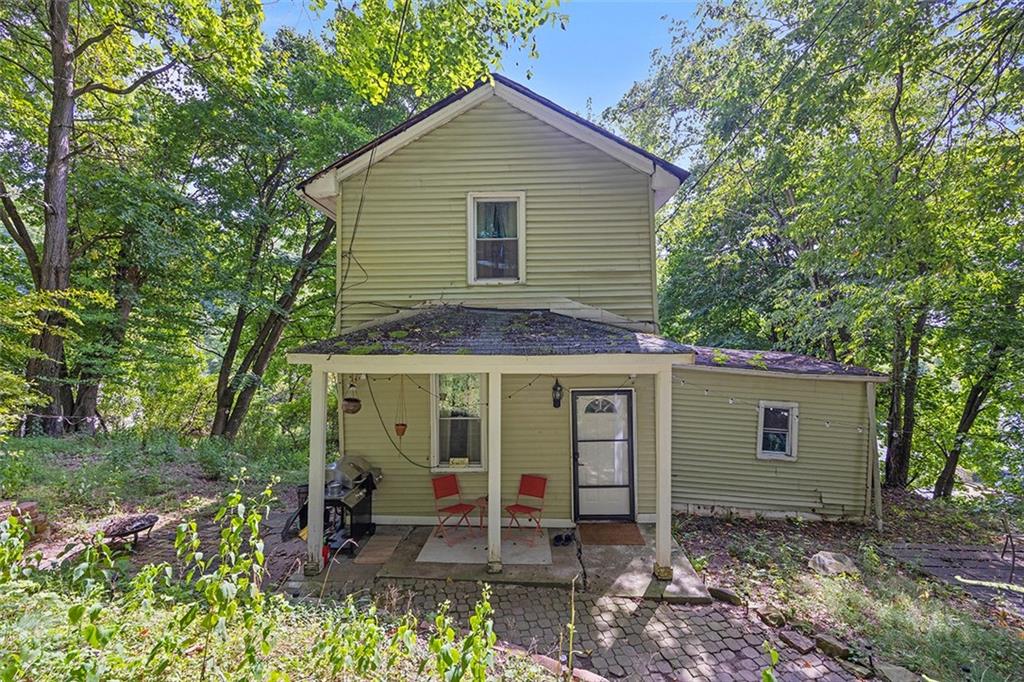 a view of a house with a yard and lawn chairs with a large tree