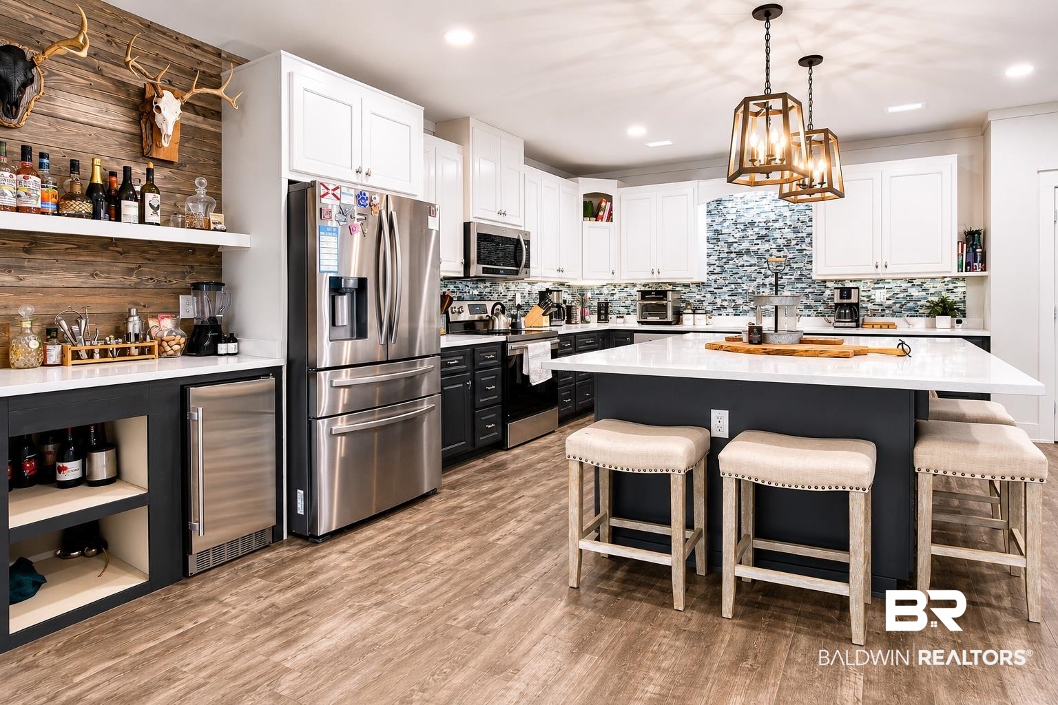9825 Wolf Creek Ridge Elberta, AL 36530 - Photo 29 of 76 Modern kitchen featuring wood-finish flooring, white upper cabinetry, dark lower cabinetry, stainless steel appliances, a mosaic tile backsplash, and a large central island with a solid surface countertop