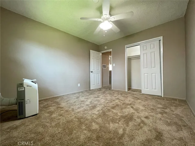 an empty room with windows and ceiling fan