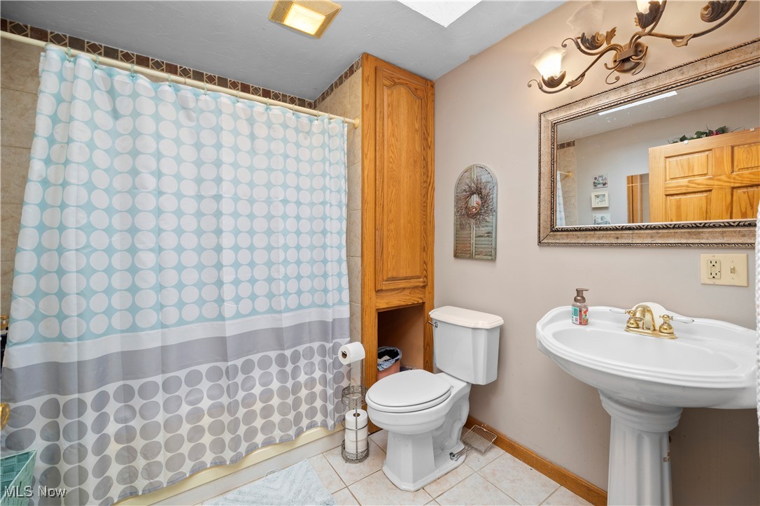 14951 Rickel Road West Salem, OH 44287 - Photo 9 of 46 Full bathroom featuring light tile patterned floors, curtained shower, and a skylight