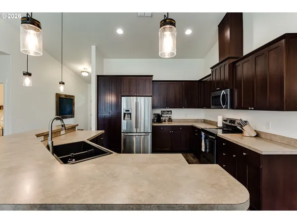 a kitchen with granite countertop a refrigerator a sink dishwasher with a stove and cabinets