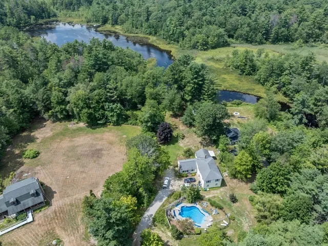 an aerial view of residential house with outdoor space and trees all around
