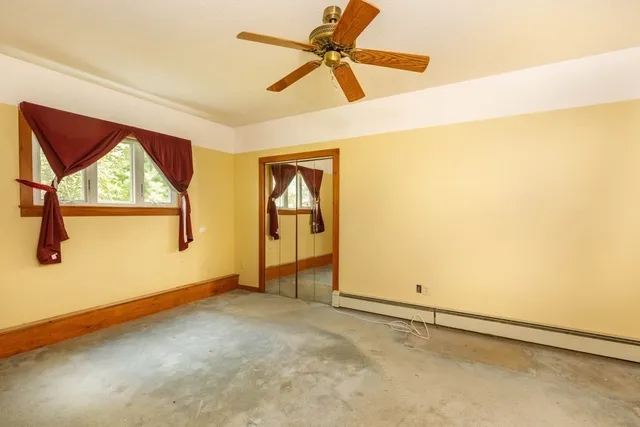 an empty room with windows and fan