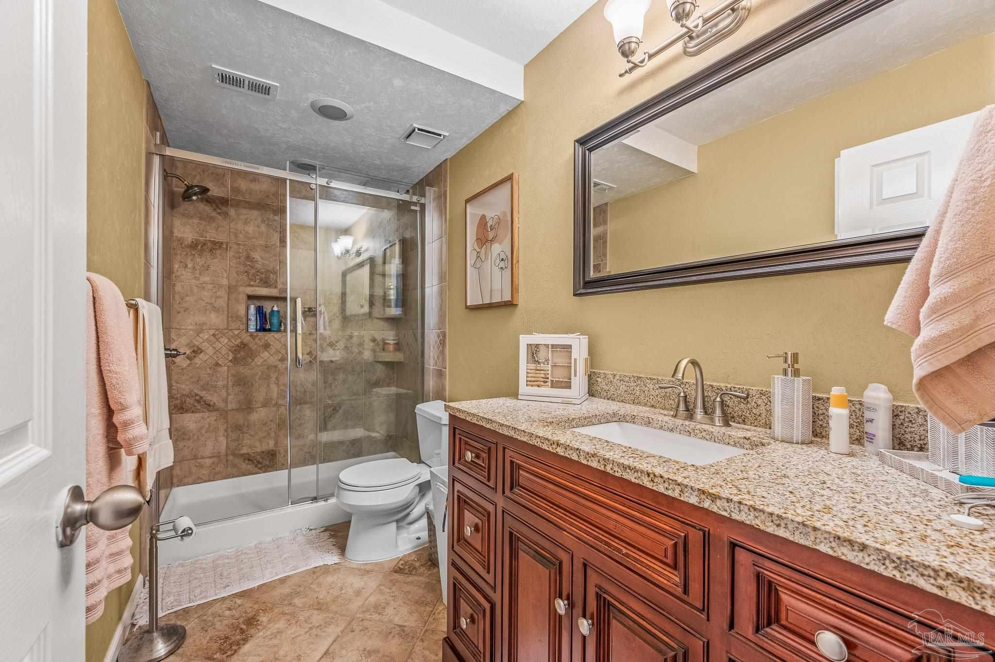 601 East Burgess Road, Unit K1 Pensacola, FL 32504 - Photo 28 of 41 a bathroom with a granite countertop sink a toilet a mirror and shower