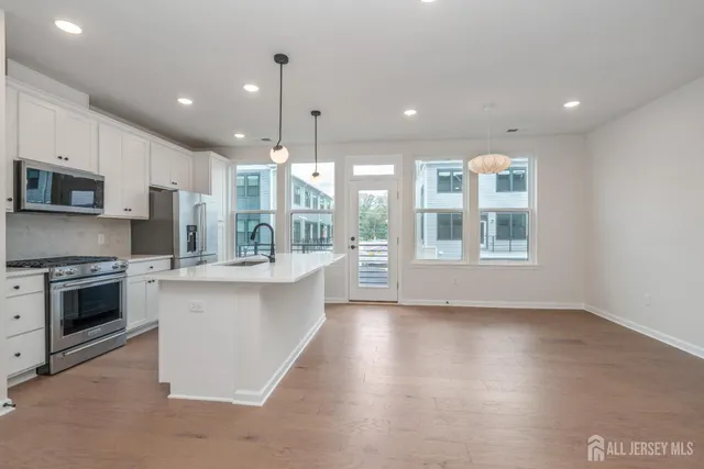 a open kitchen with kitchen island a stove a sink and a microwave