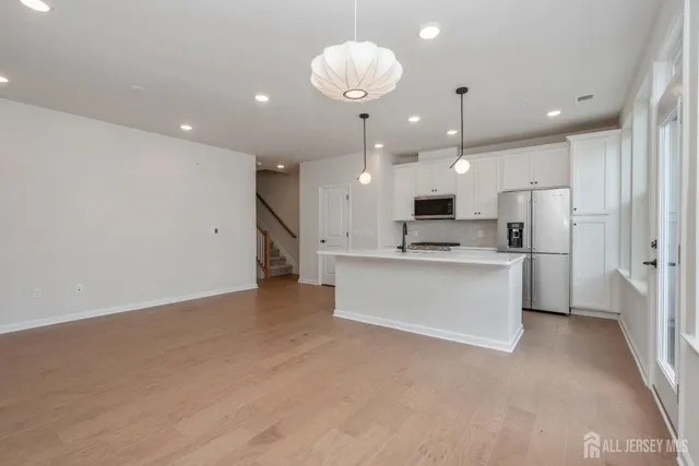 a view of kitchen with kitchen island white cabinets and refrigerator