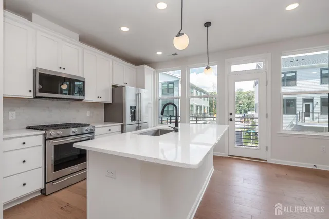 a large kitchen with stainless steel appliances granite countertop a stove a sink dishwasher and a refrigerator with wooden floor