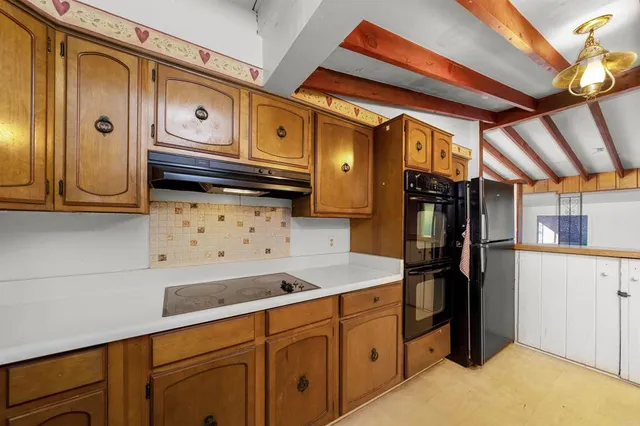 a kitchen with granite countertop a refrigerator and cabinets