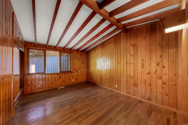 a view of an empty room with wooden floor and stairs