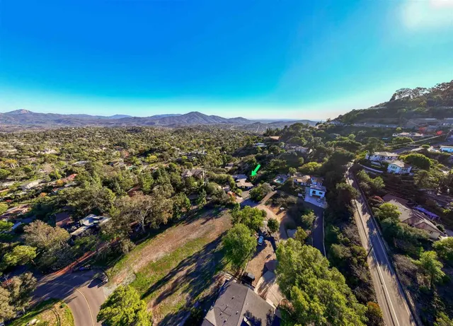 an aerial view of residential houses with outdoor space and trees