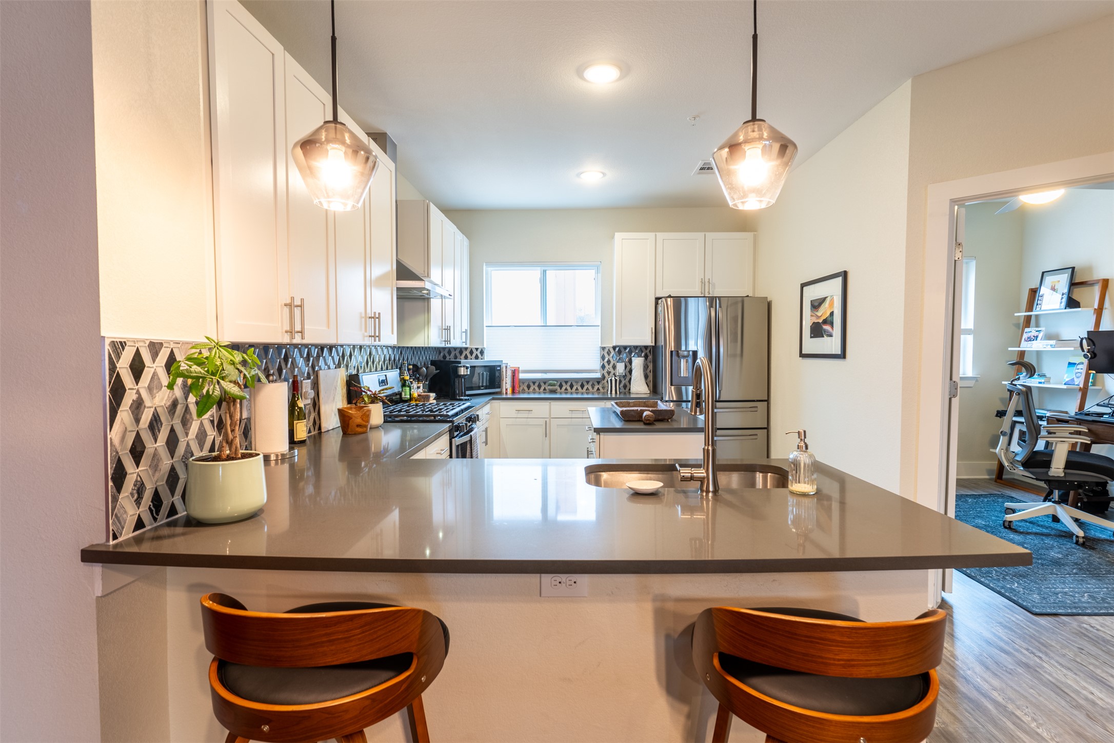 A contemporary kitchen features sleek countertops, stainless steel appliances, and stylish pendant lighting.