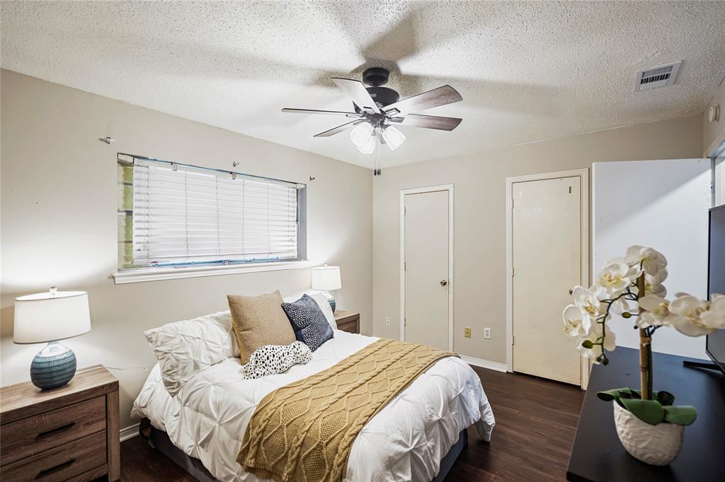 1203 Springbrook Circle DeSoto, TX 75115 - Photo 12 of 27 Bedroom featuring a textured ceiling, dark wood-type flooring, ceiling fan, and two closets