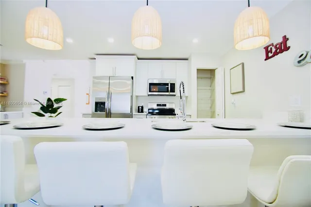 a kitchen with stainless steel appliances kitchen island granite countertop a sink and a refrigerator