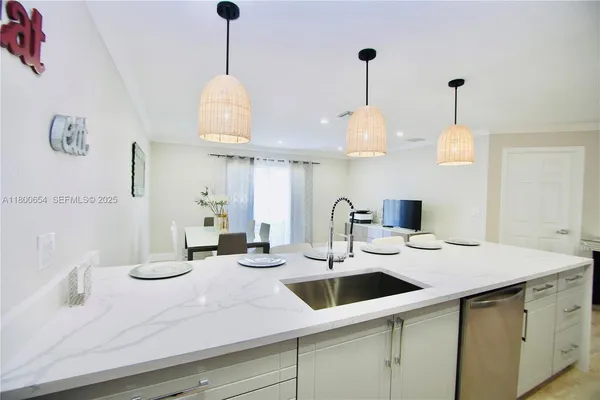 a kitchen with a sink a chandelier and living room view