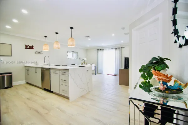 a large white kitchen with stainless steel appliances granite countertop a sink dishwasher a stove and white cabinets with wooden floor