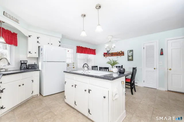 a kitchen with granite countertop a white refrigerator a sink dishwasher and white cabinets with wooden floor