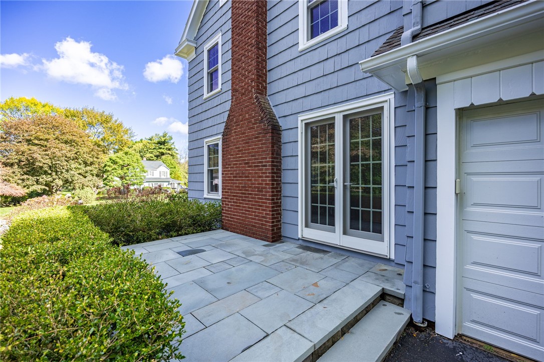387 Kilbourn Road Rochester, NY 14618 - Photo 33 of 42 A Bluestone patio sits alongside the shingle siding and a prominent brick chimney.