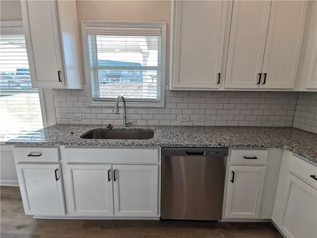 a kitchen with white cabinets appliances and window