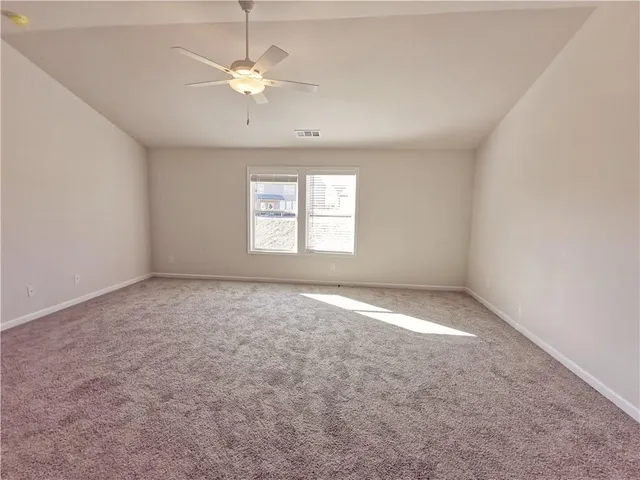 an empty room with windows and ceiling fan