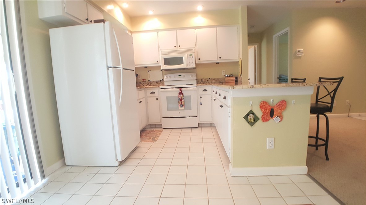 2332 Caladium Road Fort Myers, FL 33905 - Photo 7 of 17 a kitchen with white cabinets a refrigerator and a stove