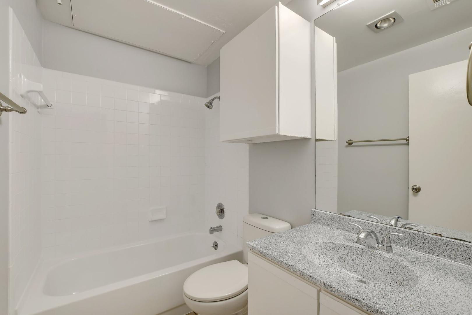 2804 Rio Grande Street, Unit 310 Austin, TX 78705 - Photo 17 of 22 A well-appointed bathroom with a spacious vanity, tiled shower-tub combo, and convenient overhead cabinetry.