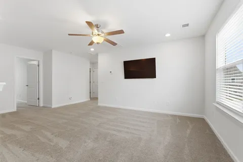 an empty room with windows and fan