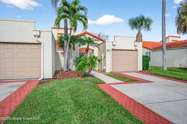 a view of yellow house with a yard and palm trees