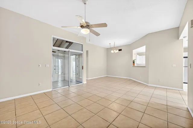 a view of an empty room and window and chandelier fan