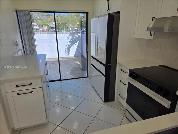 a view of a kitchen with fridge and wooden floor