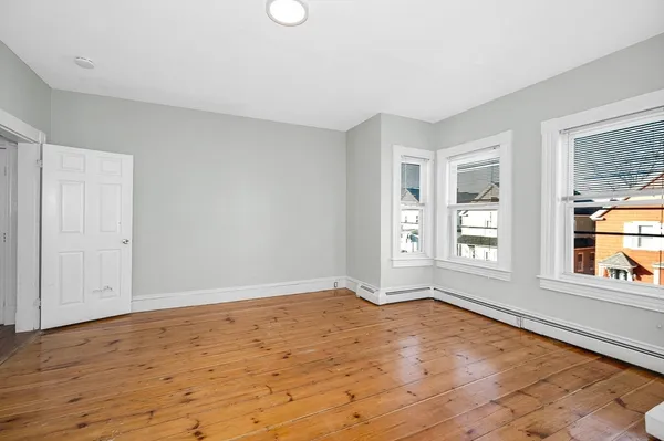 a view of an empty room with wooden floor and a window