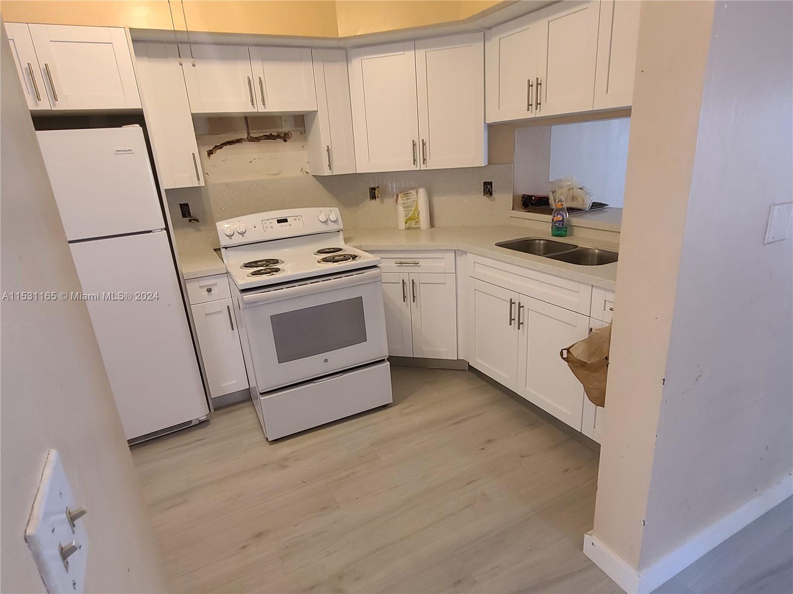 8807 Southwest 130th Place, Unit 102 Miami, FL 33186 - Photo 7 of 18 a kitchen with a white stove top oven and white cabinets