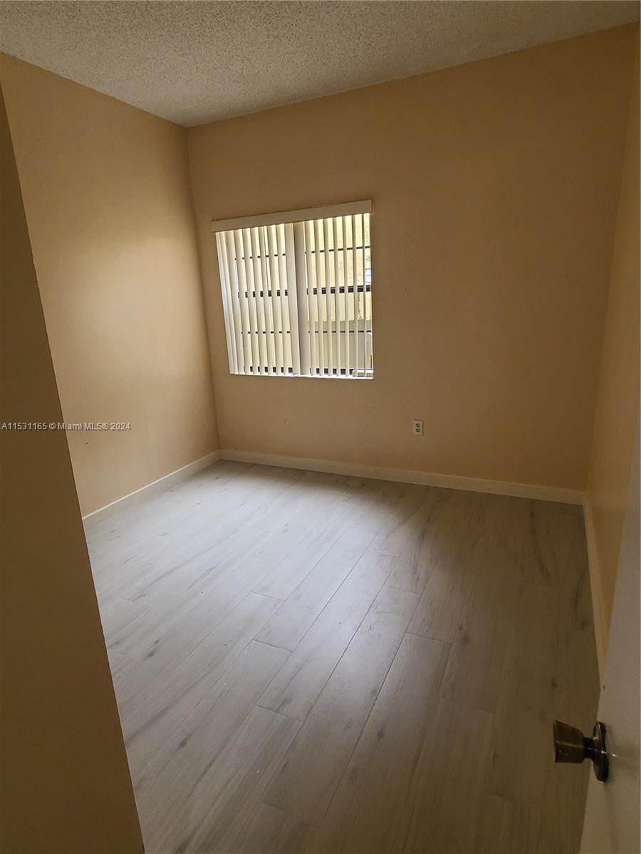 8807 Southwest 130th Place, Unit 102 Miami, FL 33186 - Photo 9 of 18 an empty room with wooden floor and windows